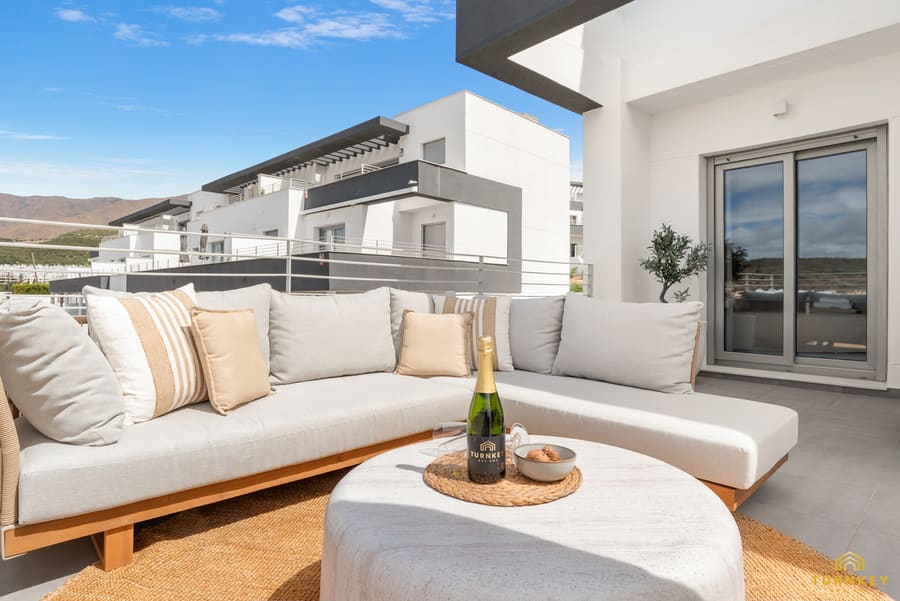 Loungehoek op het terras met een ronde stenen tafel en de zee op de achtergrond
